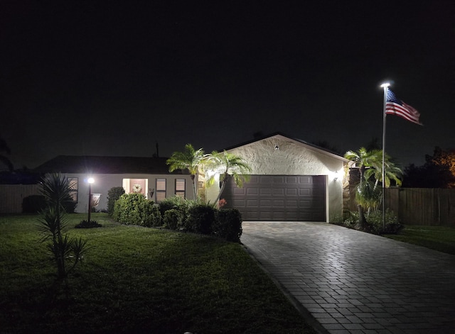 single story home with fence, an attached garage, a yard, stucco siding, and decorative driveway