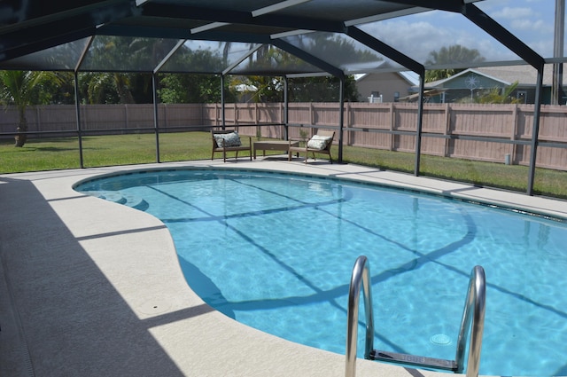 view of pool with a yard, a fenced in pool, a patio area, glass enclosure, and a fenced backyard