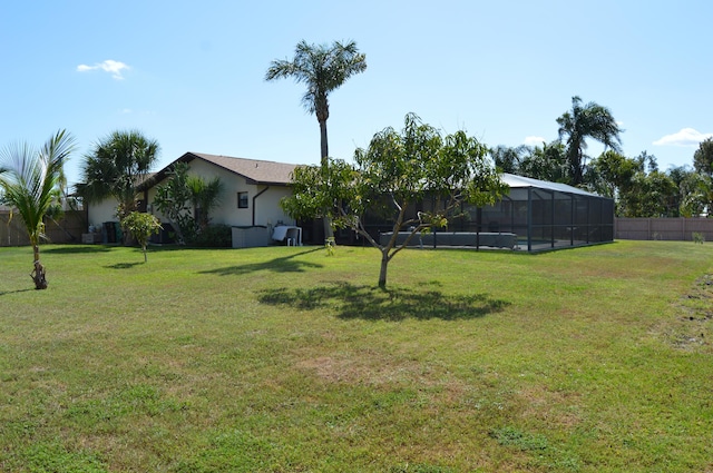 view of yard with glass enclosure and fence