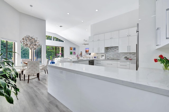 kitchen featuring light stone counters, tasteful backsplash, hanging light fixtures, white cabinetry, and a peninsula