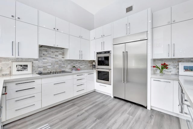 kitchen featuring stainless steel appliances, tasteful backsplash, light countertops, visible vents, and white cabinetry