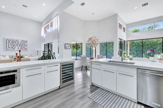 kitchen with beverage cooler, visible vents, appliances with stainless steel finishes, light countertops, and white cabinetry