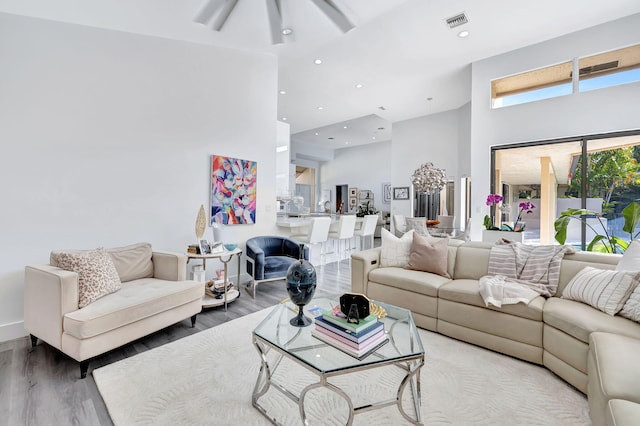 living area with a high ceiling, visible vents, wood finished floors, and recessed lighting