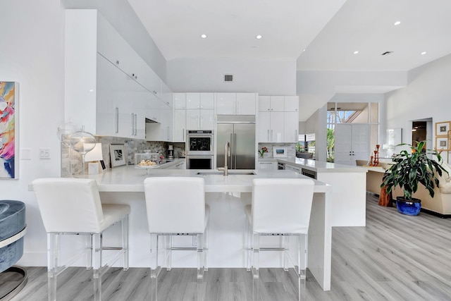 kitchen with stainless steel appliances, light countertops, a peninsula, and a kitchen bar