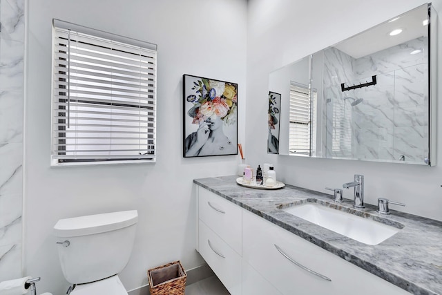 bathroom featuring toilet, a marble finish shower, and vanity