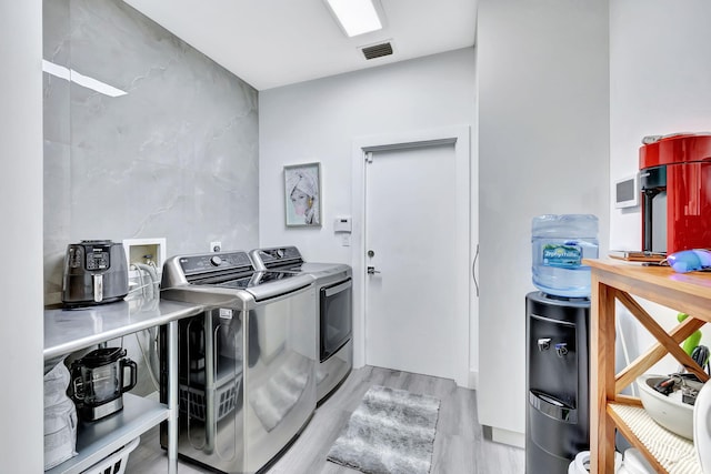 washroom featuring light wood-style floors, laundry area, visible vents, and washing machine and clothes dryer