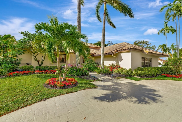 mediterranean / spanish-style house with a tiled roof, a front lawn, and stucco siding