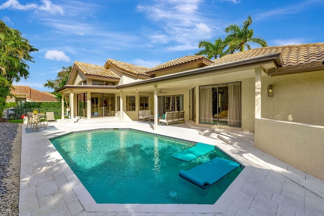 rear view of property with ceiling fan, a patio, fence, a tiled roof, and an outdoor pool