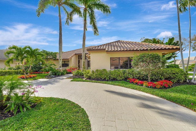 mediterranean / spanish-style house with a front yard, a tile roof, and stucco siding