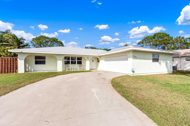 ranch-style home featuring a garage, concrete driveway, a front lawn, central AC, and stucco siding