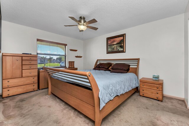 bedroom featuring light carpet, ceiling fan, a textured ceiling, and baseboards