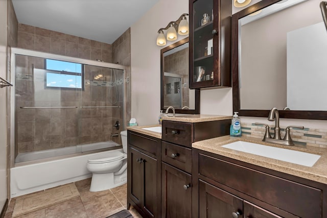 bathroom with double vanity, shower / bath combination with glass door, a sink, and toilet