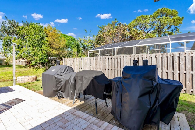 view of patio featuring glass enclosure, grilling area, and fence