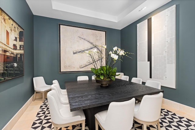 dining space featuring a tray ceiling, tile patterned floors, and baseboards