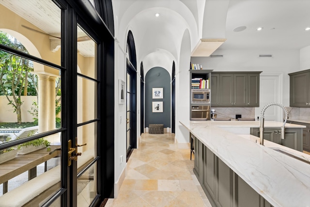 interior space with decorative backsplash, light stone counters, appliances with stainless steel finishes, gray cabinets, and recessed lighting