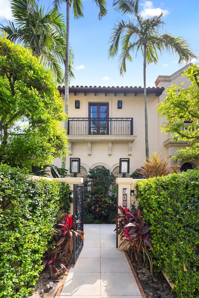 view of front of property featuring french doors, a tile roof, a balcony, and stucco siding