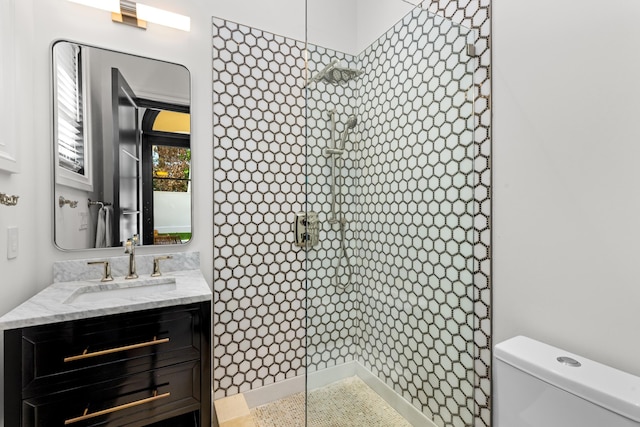 full bath featuring vanity, a tile shower, and toilet