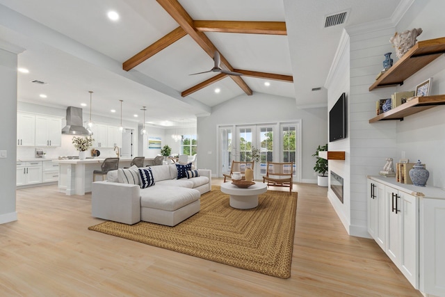 living area featuring high vaulted ceiling, a fireplace, visible vents, light wood-style floors, and beamed ceiling