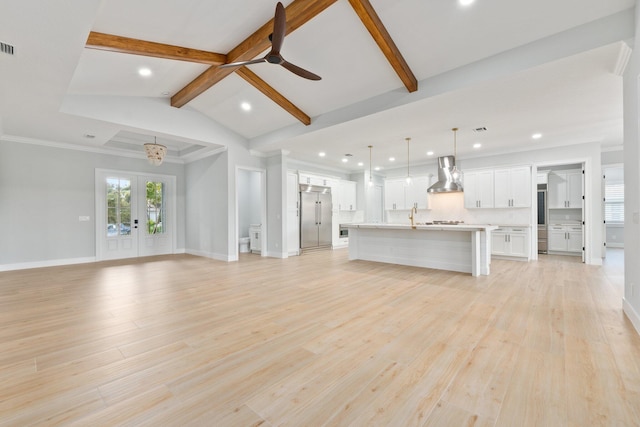 unfurnished living room with lofted ceiling with beams, light wood-style flooring, baseboards, and french doors