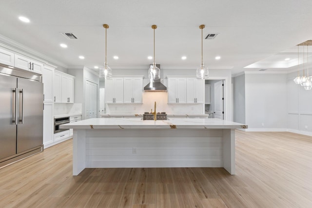 kitchen with pendant lighting, a spacious island, visible vents, appliances with stainless steel finishes, and wall chimney exhaust hood