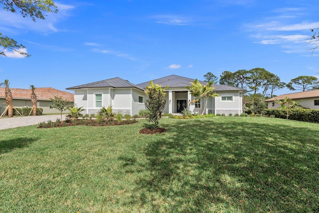 view of front of house featuring driveway, a standing seam roof, metal roof, and a front yard