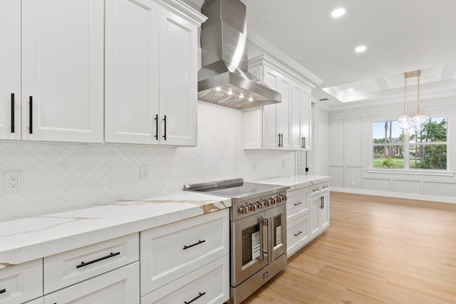 kitchen with light wood finished floors, tasteful backsplash, stainless steel range, white cabinets, and wall chimney exhaust hood