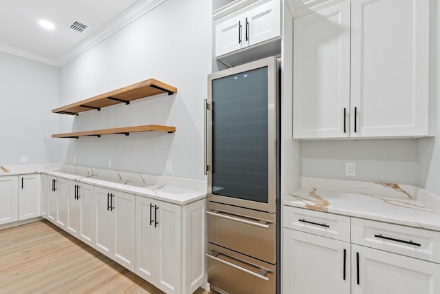 kitchen with light stone countertops, visible vents, white cabinets, and ornamental molding