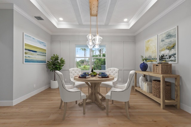 dining room featuring light wood-style floors, visible vents, a decorative wall, and ornamental molding