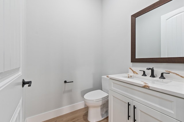 bathroom featuring wood finished floors, vanity, toilet, and baseboards