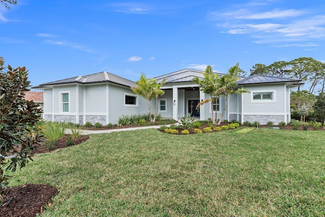 view of front of home featuring a front yard, stone siding, metal roof, and a standing seam roof