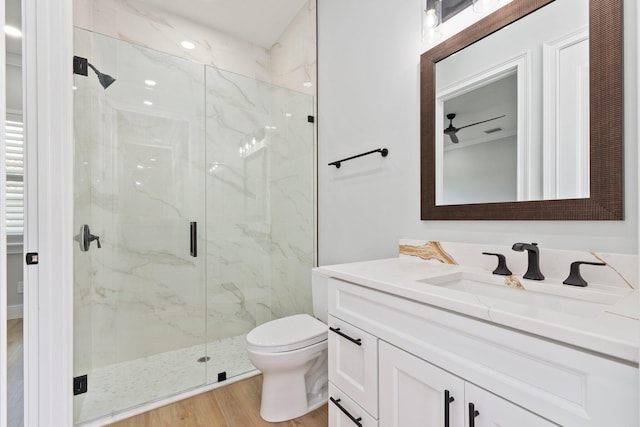 full bathroom featuring toilet, vanity, a marble finish shower, and wood finished floors