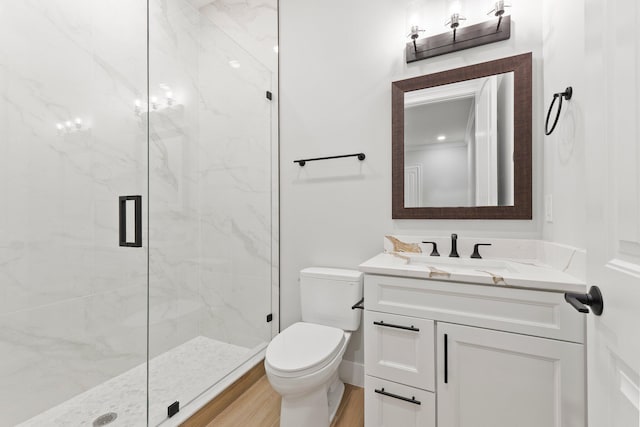 full bathroom featuring toilet, a marble finish shower, wood finished floors, and vanity