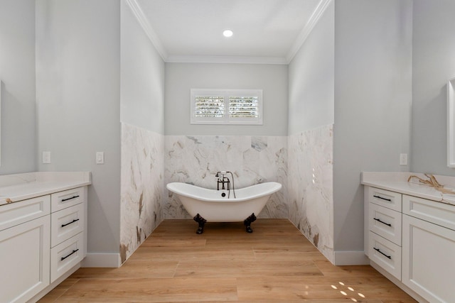 bathroom featuring a soaking tub, crown molding, vanity, and wood finished floors