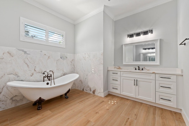 bathroom with wood finished floors, vanity, tile walls, a freestanding bath, and ornamental molding