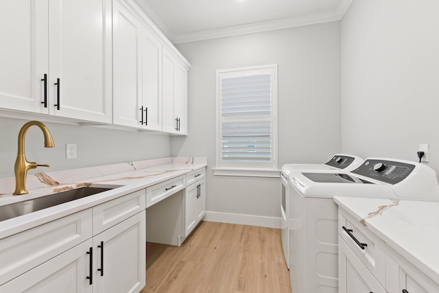 clothes washing area featuring a sink, ornamental molding, light wood-type flooring, cabinet space, and washer and clothes dryer