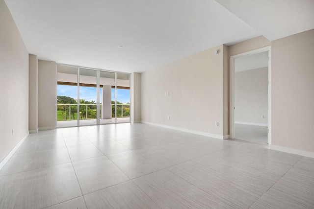 spare room featuring a wall of windows and baseboards