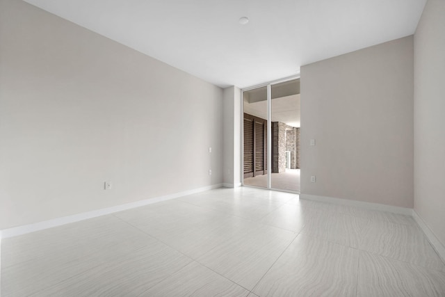 unfurnished room with a healthy amount of sunlight, baseboards, and a wall of windows