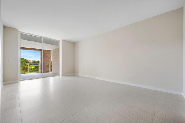 unfurnished room featuring baseboards and a wall of windows