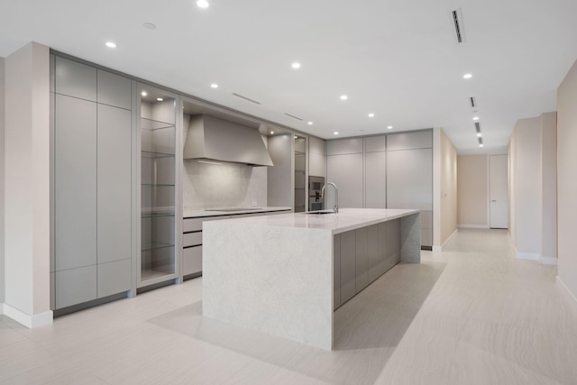 kitchen with gray cabinets, a large island, wall chimney range hood, and modern cabinets