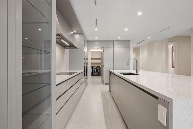 kitchen featuring modern cabinets, light countertops, black electric cooktop, gray cabinetry, and a sink