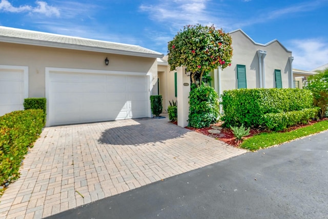 view of front of home featuring decorative driveway, an attached garage, and stucco siding