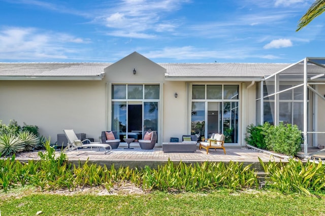 back of house featuring glass enclosure, a tile roof, outdoor lounge area, and stucco siding