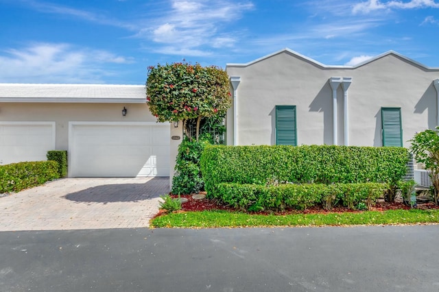 view of front of property featuring a garage, decorative driveway, and stucco siding