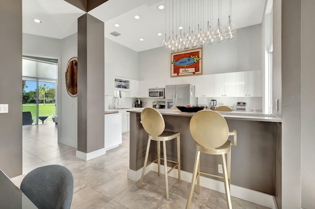 kitchen with a peninsula, white cabinetry, appliances with stainless steel finishes, and light countertops