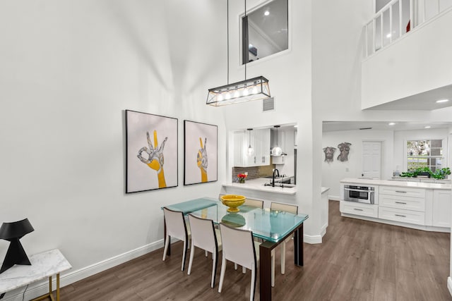 dining space with a high ceiling, wood finished floors, visible vents, and baseboards