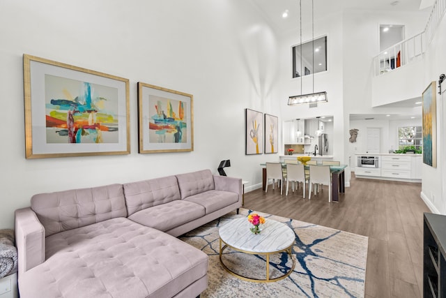 living room with a towering ceiling, baseboards, and wood finished floors