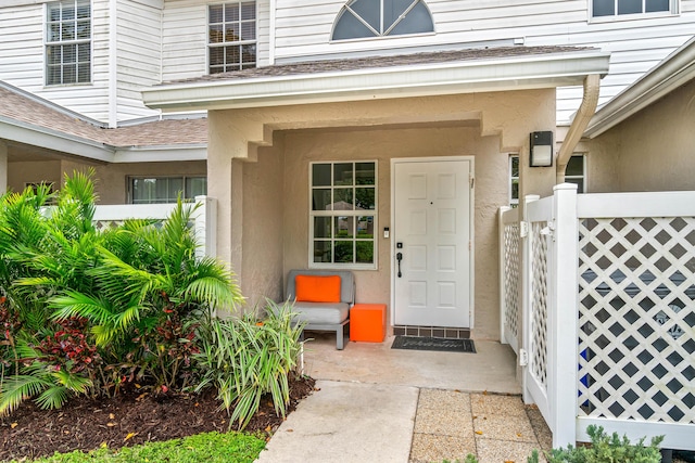 doorway to property featuring roof with shingles and stucco siding