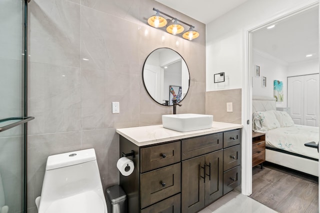 ensuite bathroom with toilet, vanity, tile walls, and ensuite bathroom