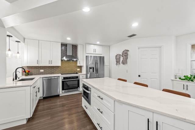 kitchen featuring tasteful backsplash, visible vents, wall chimney exhaust hood, stainless steel appliances, and a sink