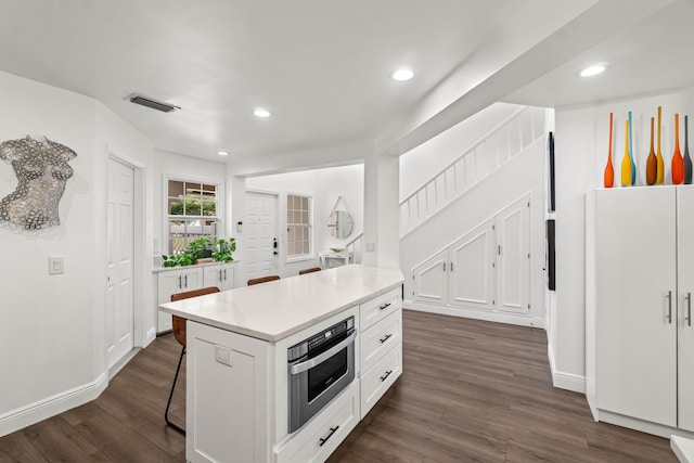 kitchen featuring dark wood-type flooring, recessed lighting, white cabinets, and visible vents